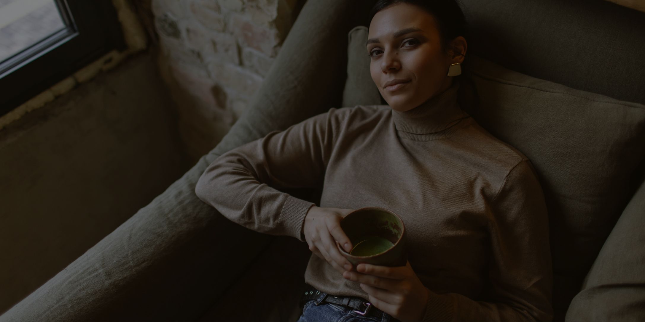 Woman relaxing with a mug in a cozy setting.