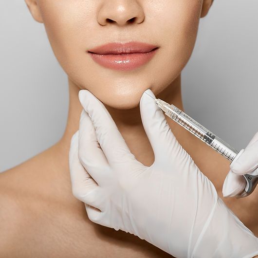 Injecting dermal filler into patient's chin area.