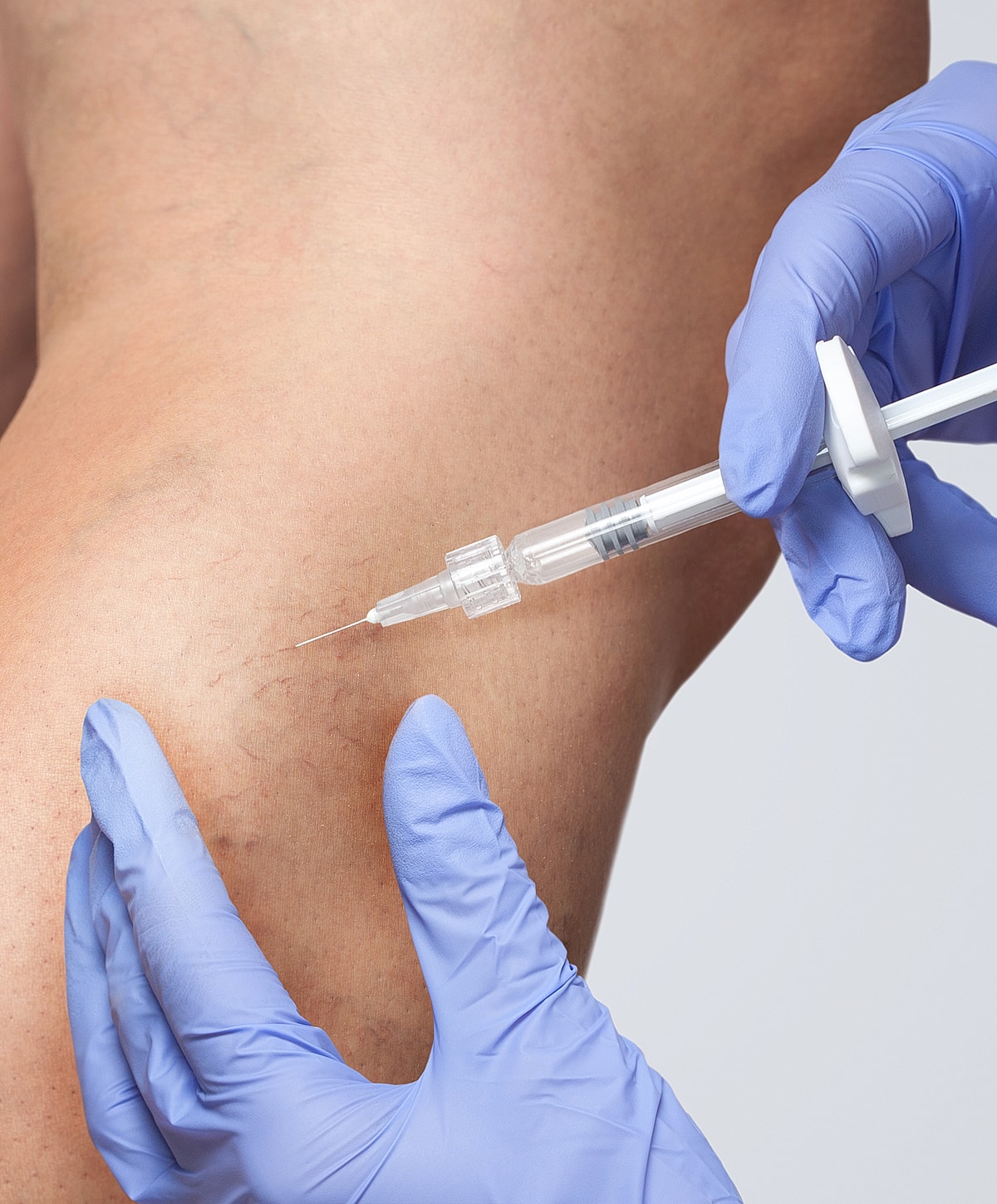 Administering injection to patient's thigh area.