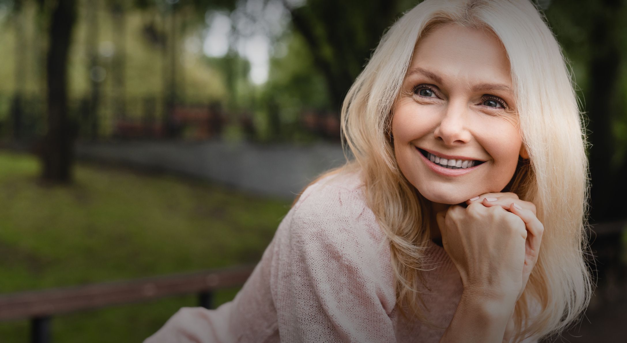 Smiling woman in a park setting.