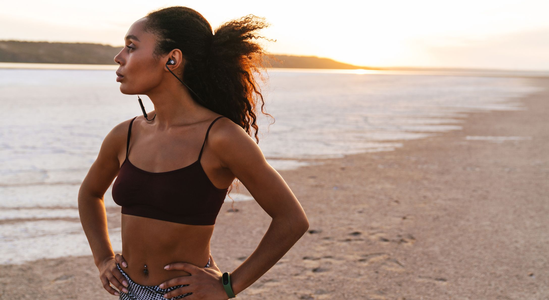 Woman in sportswear by the beach at sunset.