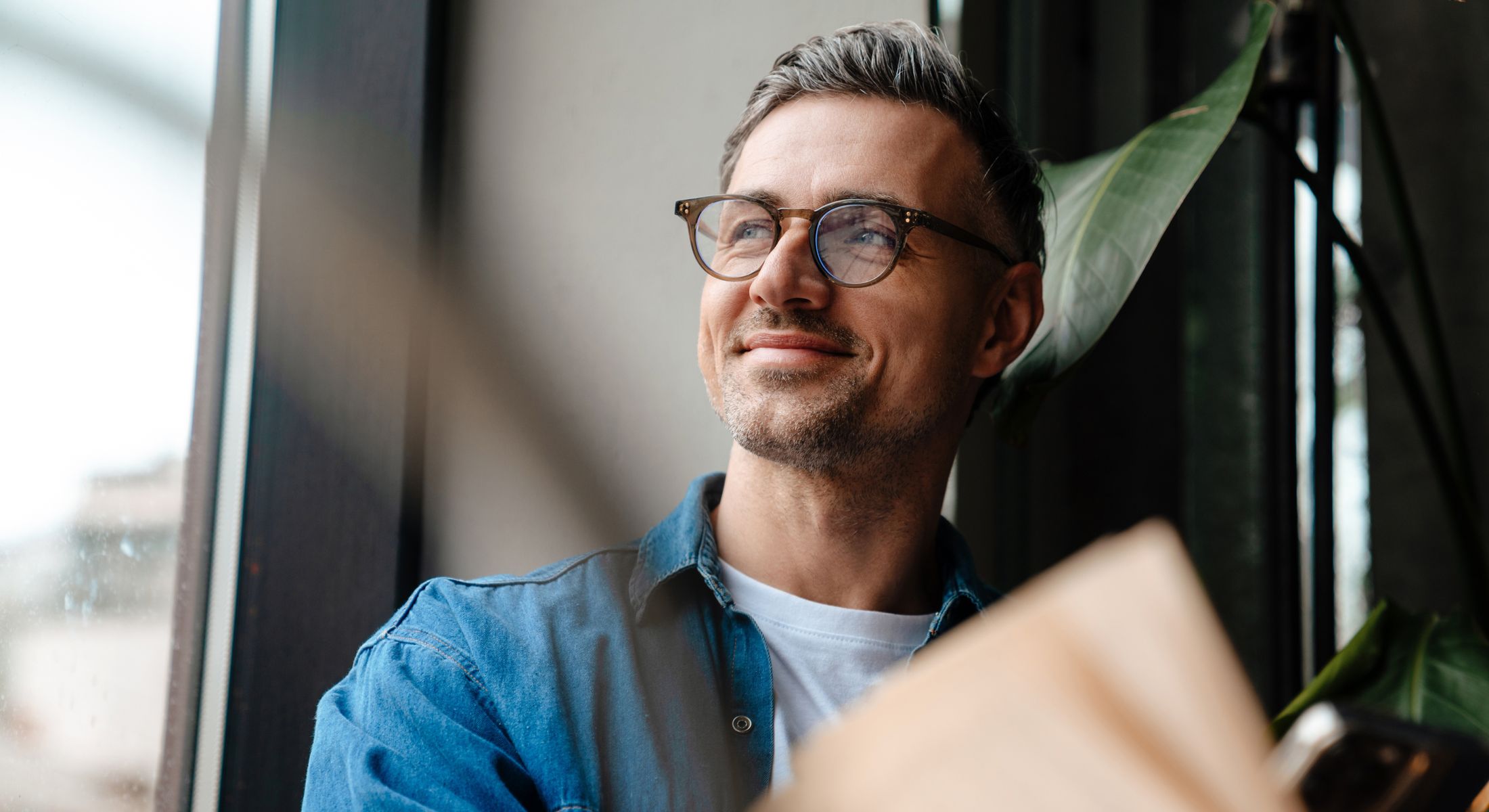 Man smiling while sitting by a window.