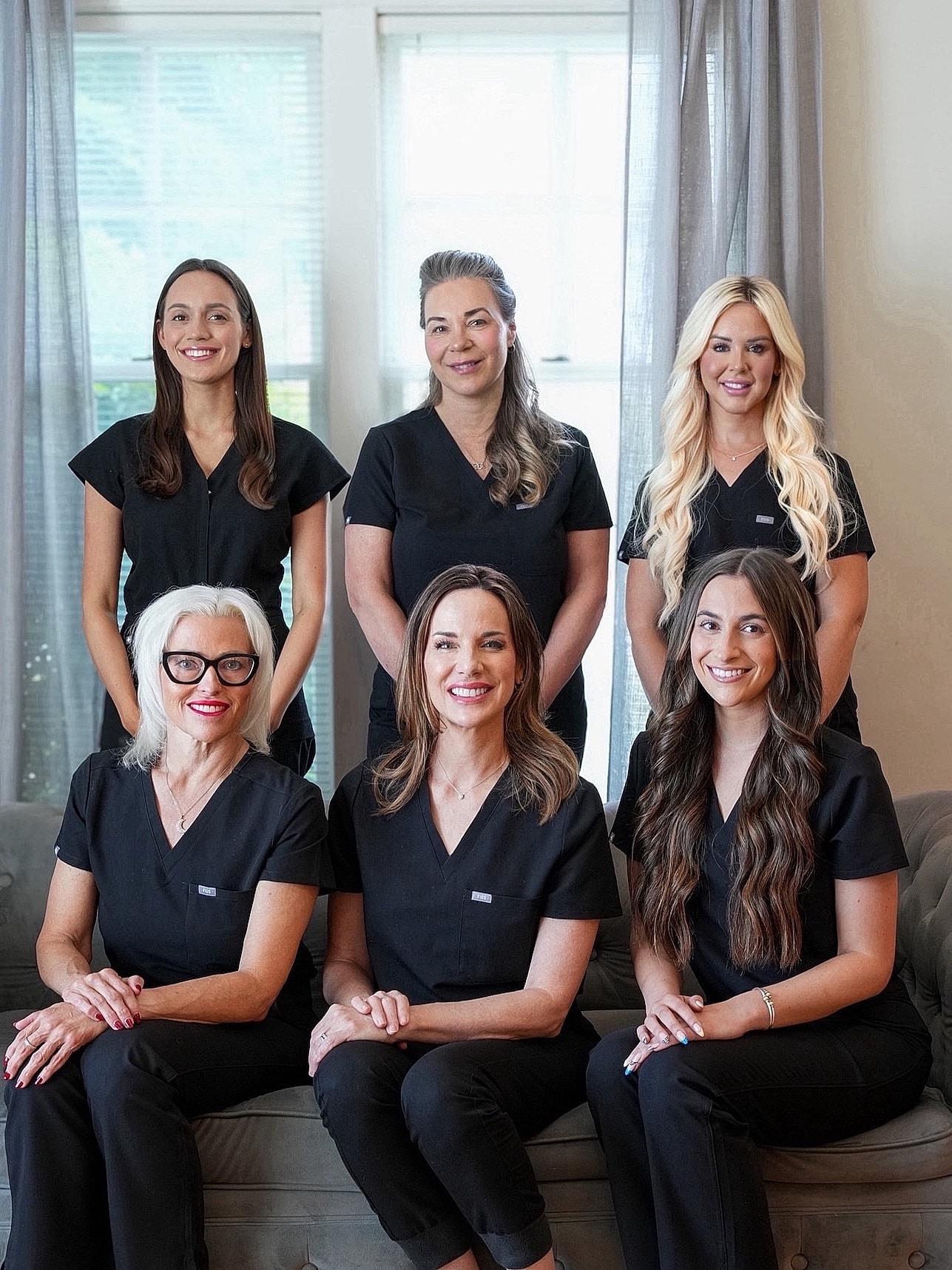 Group of professionals in black scrubs, smiling.