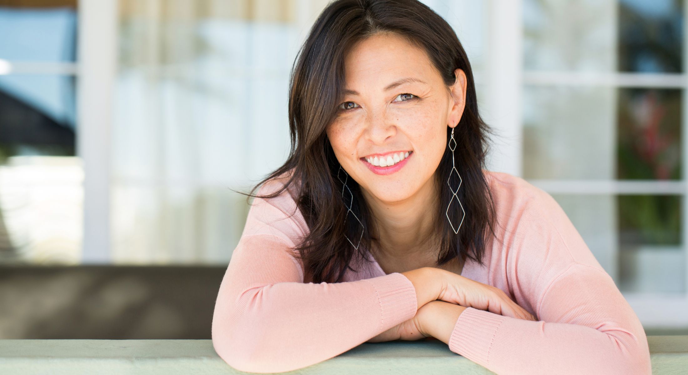 Woman smiling in a cozy indoor setting.