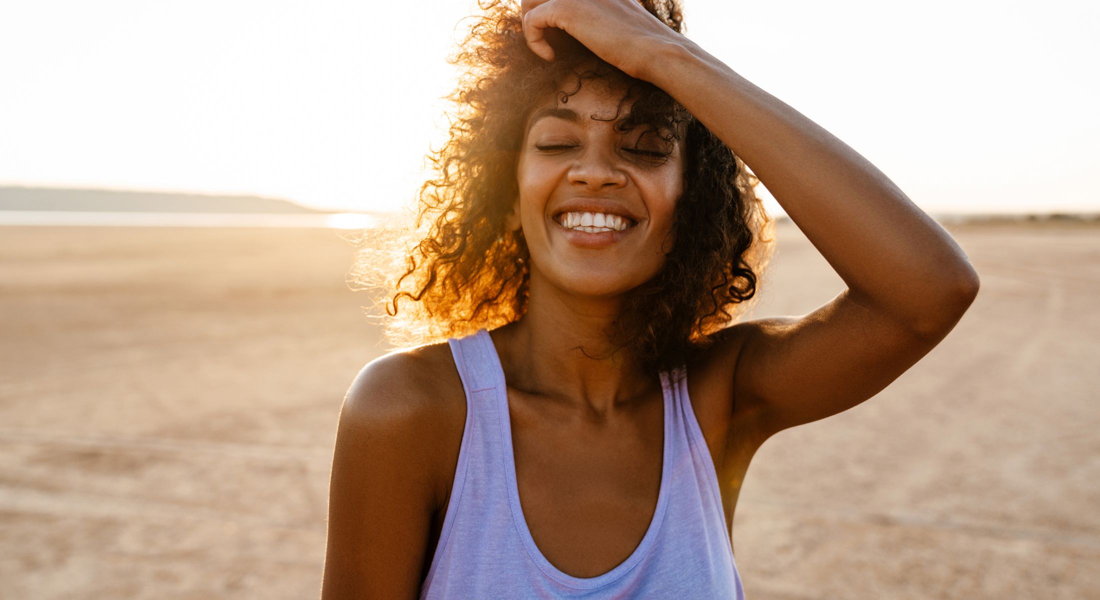 Smiling woman enjoying sunset outdoors.